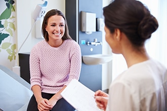 Woman talking with a health care professional in a doctor’s office.