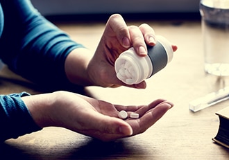 A patient pours pills from a medicine bottle.