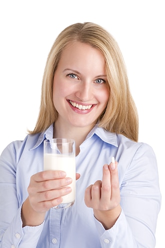امرأة تحمل كأسًا من الحليب وأقراص لاكتاز.