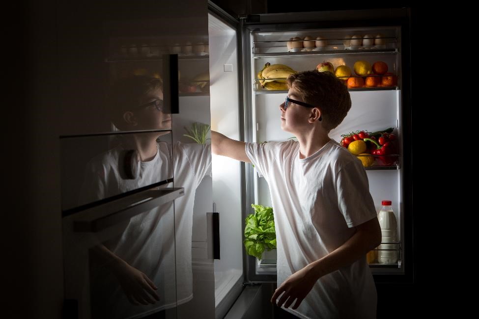 Teen looking into the refrigerator late at night.