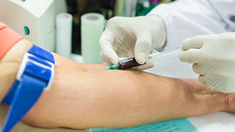 A health care professional drawing blood from a person’s arm.