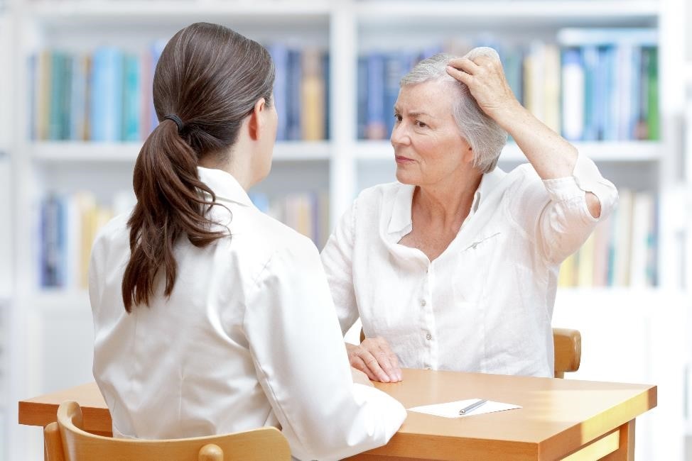 امرأة مسنة ذات شعر رمادي تظهر شعرها الخفيف للطبيبة.
