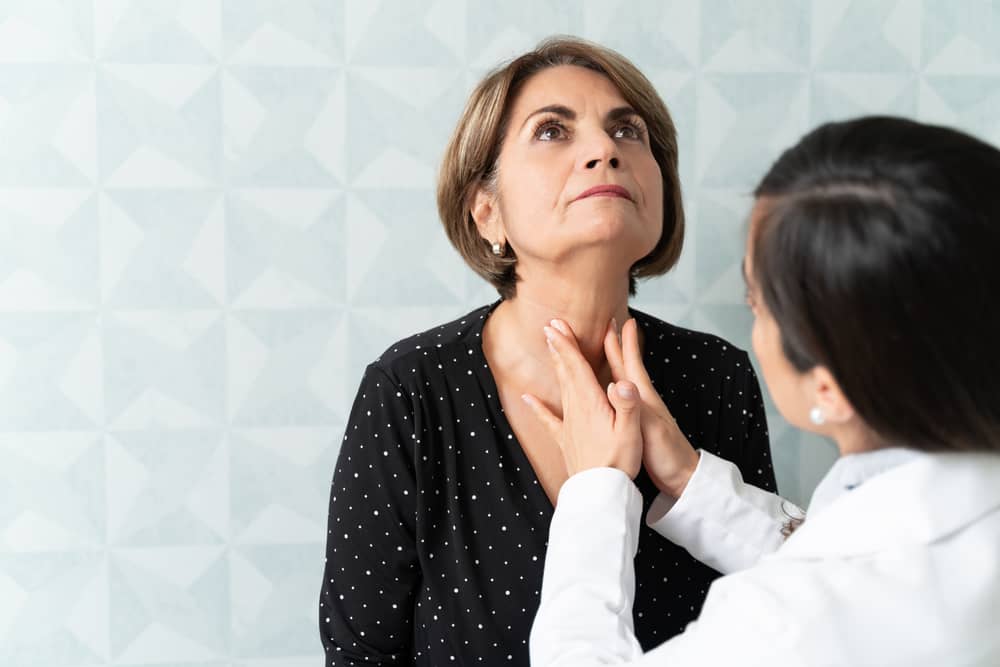 A health professional examines a woman's neck.