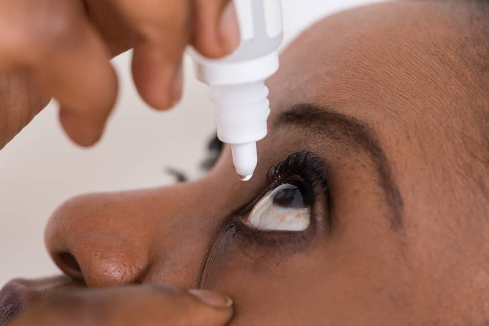 Woman putting eye drops in her eye.