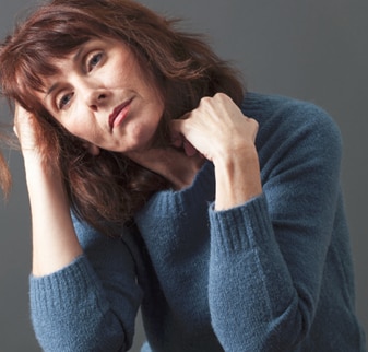 A woman with her elbows on a table and her head resting on one hand.