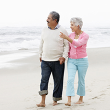 A couple holding hands and walking on the beach.