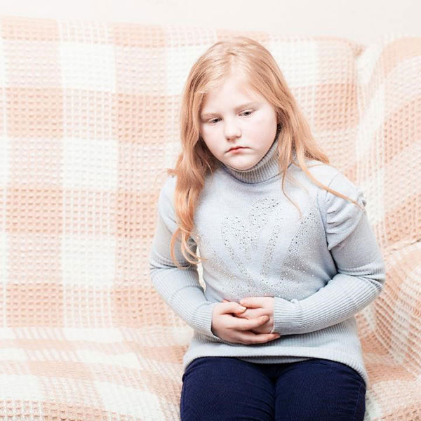 child with stomach ache on a sofa