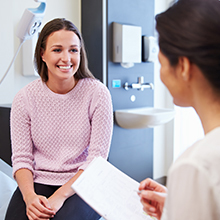 Female Patient And Doctor Have Consultation In Hospital Room