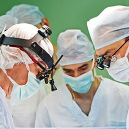 Team of surgeons in uniform perform operation on a patient