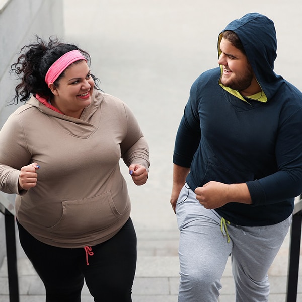 Two young people jogging up steps.
