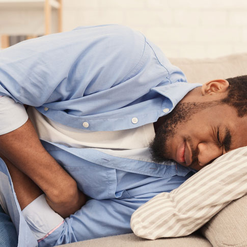 man suffering from stomach ache, lying on sofa