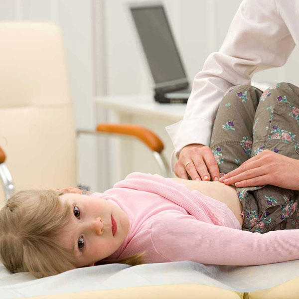 A doctor examining a young girl’s abdomen.