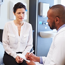 Female Patient And Doctor Have Consultation In Hospital Room