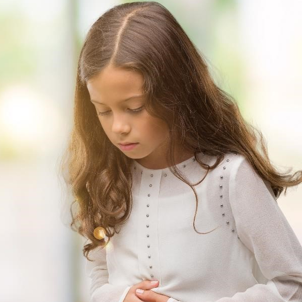 Young girl holding her stomach in pain.