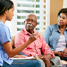 Nurse Making Notes During Home Visit With Senior Couple