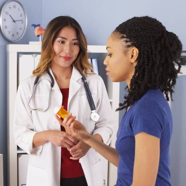 Doctor talking with a patient who is holding a medicine bottle.