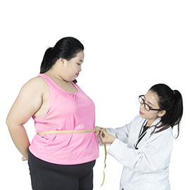 Female doctor examining belly of obese woman