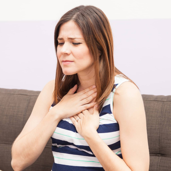 Woman has acid reflux on a park bench.