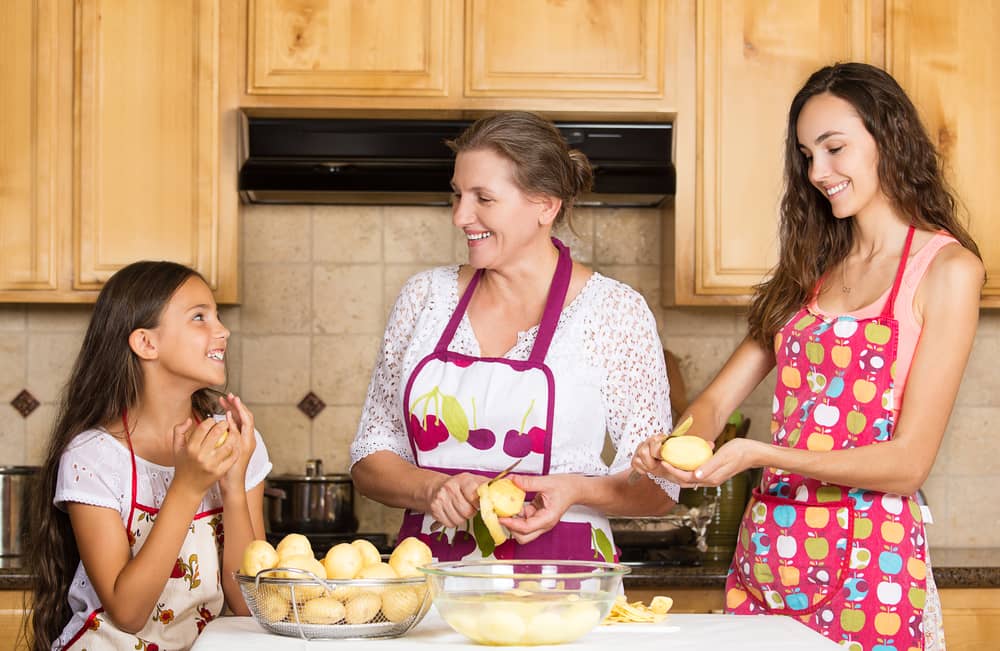 A mother and her daughters prepare a meal in the kitchen.