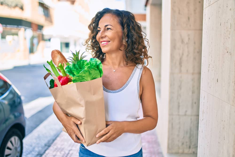 Older woman holding a bag of groceries.