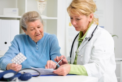 Una mujer mayor que habla con su doctora. Están mirando a un pedazo de papel.