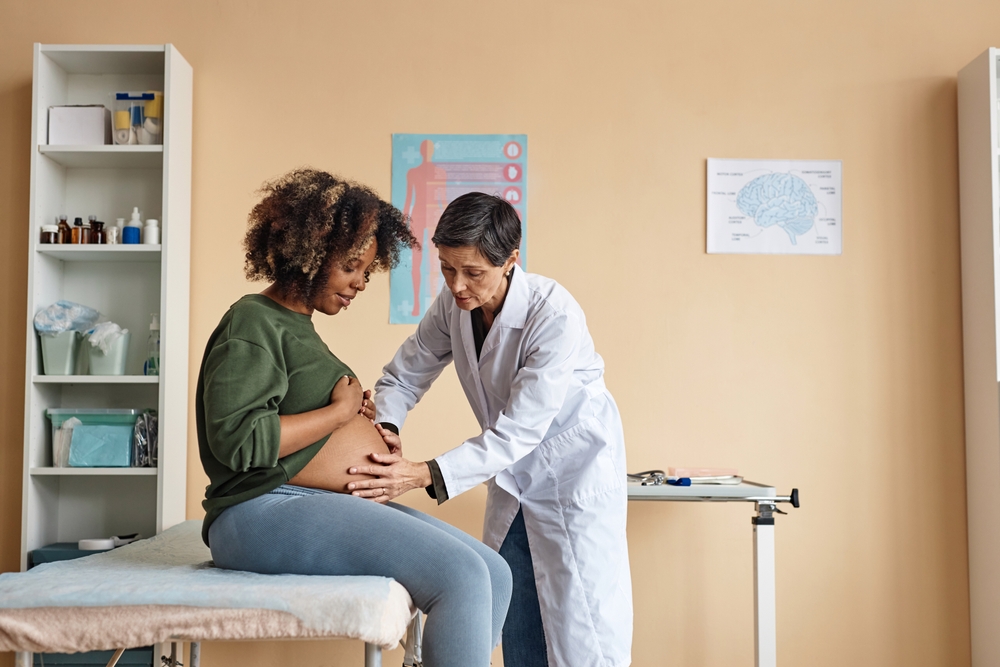 Una profesional de atención de salud examina a una mujer embarazada.