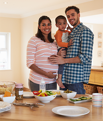 Una mujer embarazada y su familia están preparando para comer comida saludable.