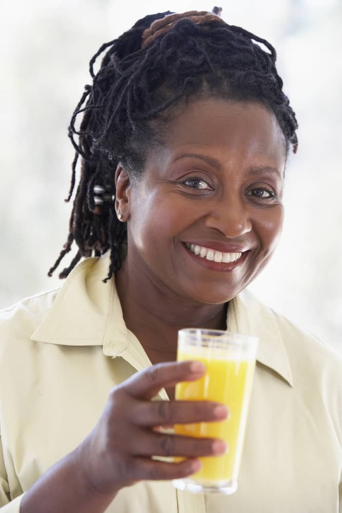A woman holds a glass of fruit juice..