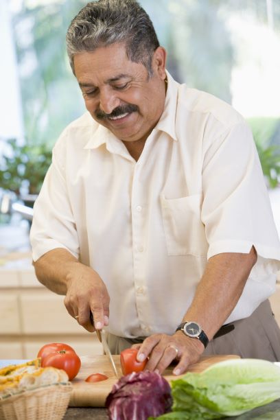 Un hombre mayor preparando la comida.