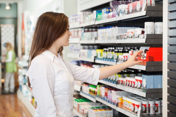 Una mujer comprando un medicamentos de venta libre en una farmacia.