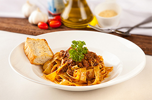 Un plato de pasta en un bol con el pan en el lado