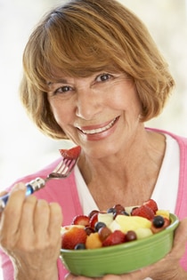 Una mujer comiendo un plato de frutas