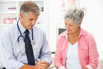 Médico hablando con una paciente y tomando notas.