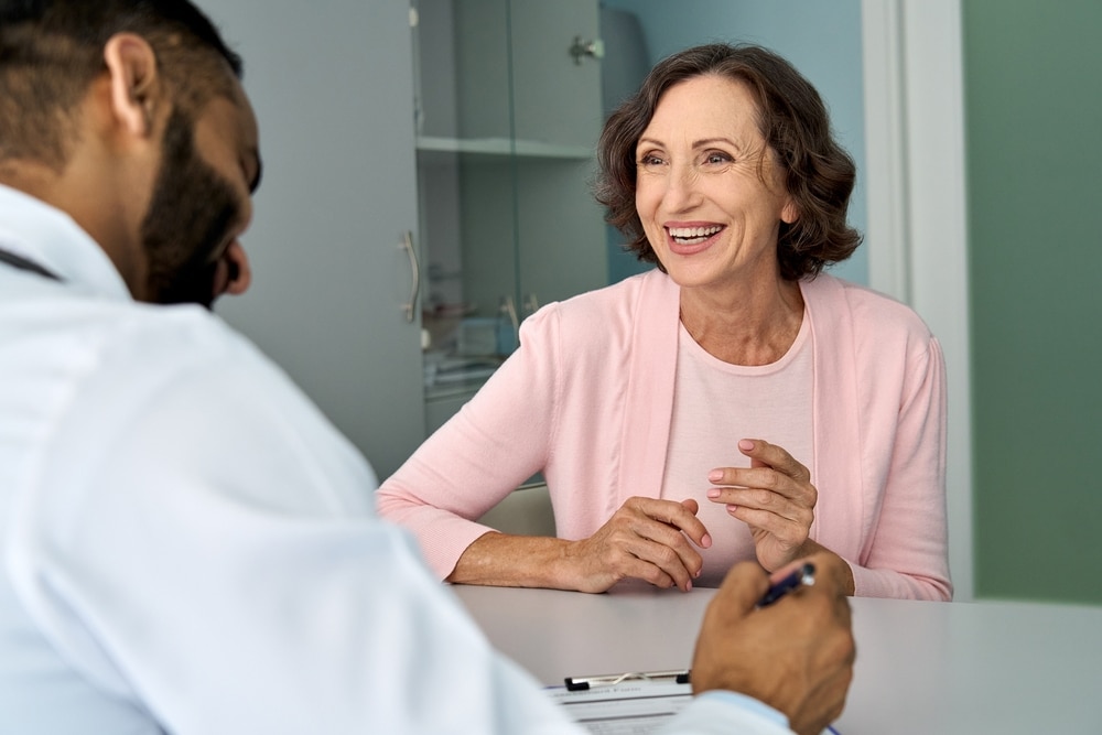 A health care professional talking with a patient who is a woman.