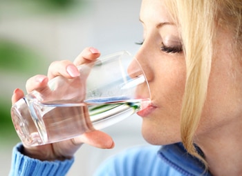Mujer que bebe un vaso de agua.
