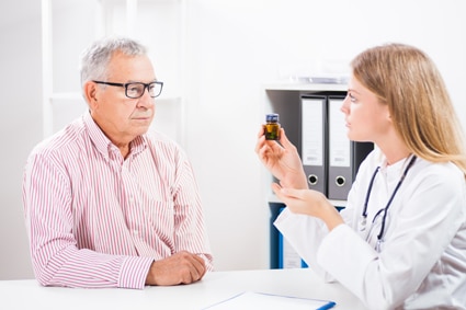 Foto de un paciente que le muestra todas las botellas de sus medicinas a un médico.