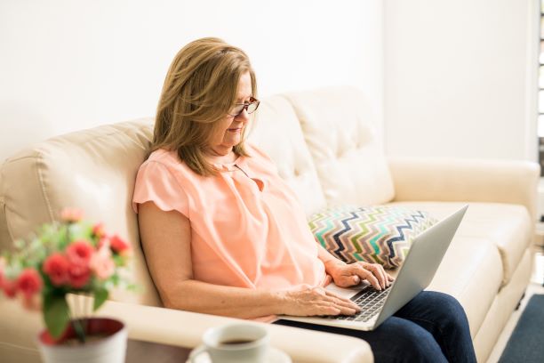 امرأة تستخدم الكمبيوتر المحمول الخاص بها على أريكتها.
