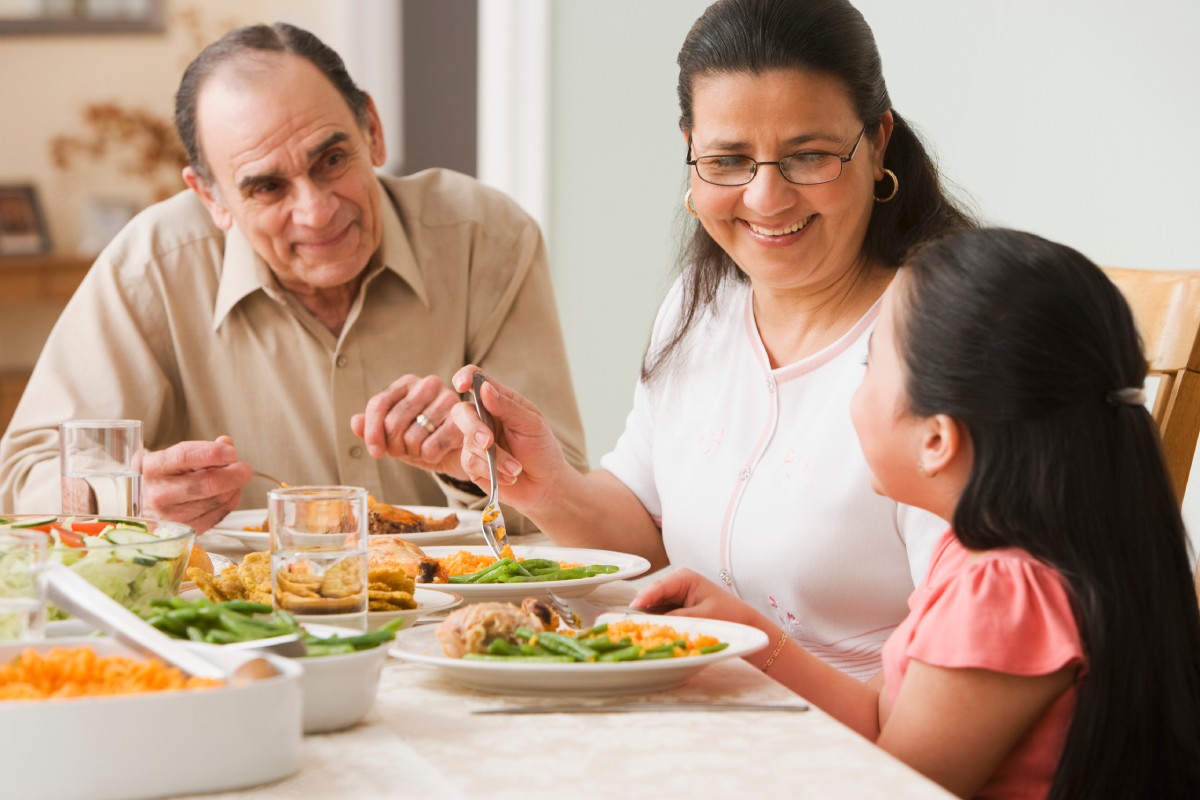 A grandfather has dinner with his daughter and granddaughter.