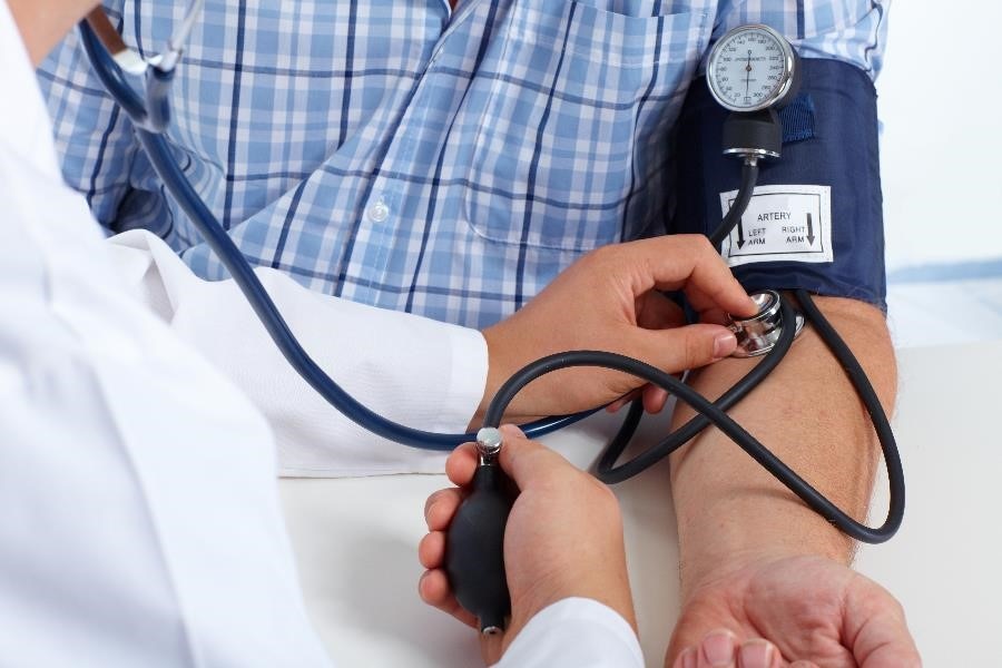 Foto que muestra un acercamiento de un médico evaluando la presión arterial de un paciente.