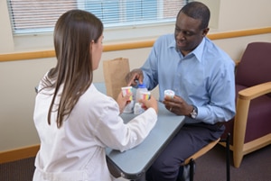 A photo of a patient showing all his medicine bottles to a health care provider.