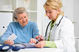 A photo of a health care provider talking about medicine to an older patient.