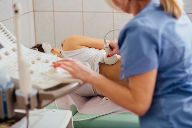 Una profesional de atención médica haciendo una ecografía del riñón de una mujer.