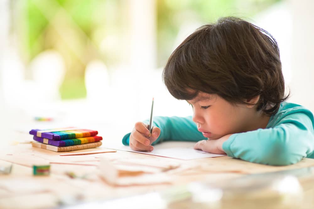 طفل يرسم على طاولة