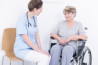 مقدم الرعاية الصحية يتحدث مع امرأة على كرسي متحرك.