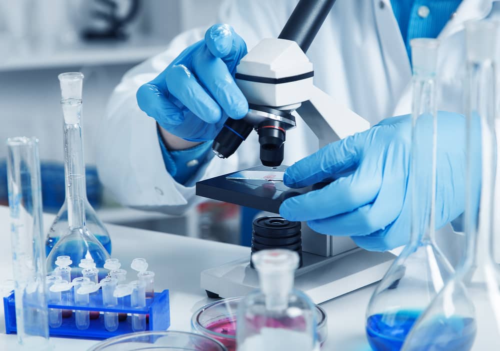 A health care professional using a microscope in a lab.