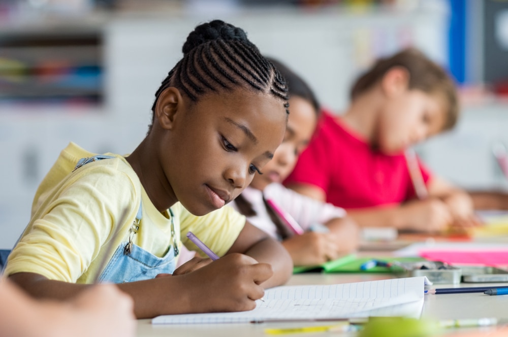 Niños haciendo tareas escolares en sus pupitres.