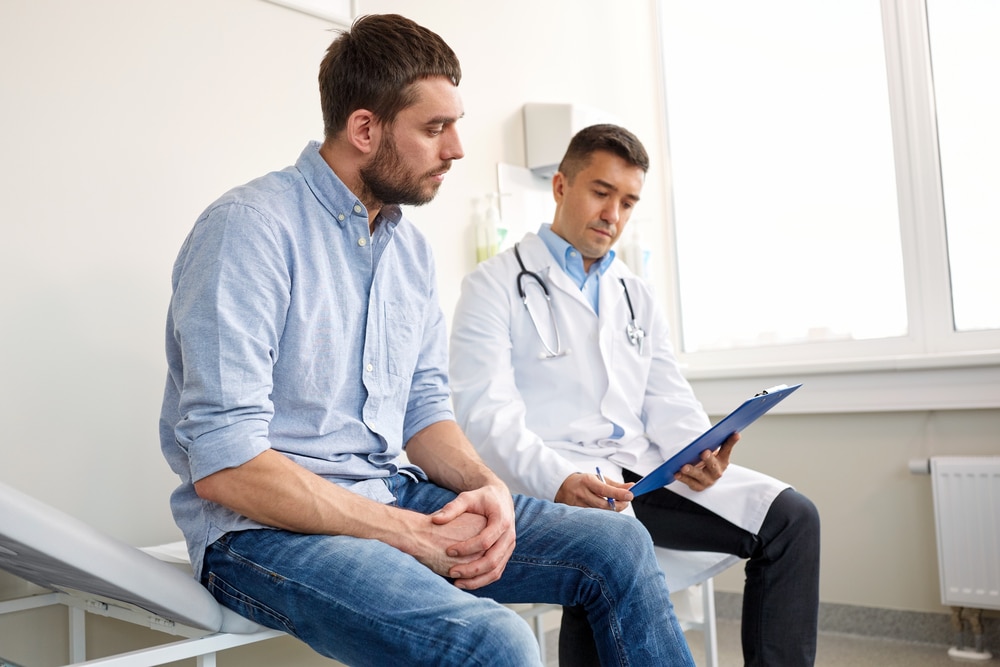 Health care professional reviews information on a medical chart with a patient in an examination room.