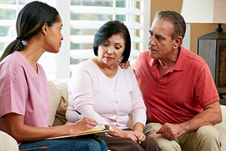 A couple meets with a health care professional in their home.