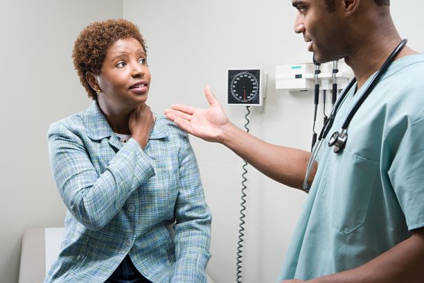 A woman in an exam room talks to her health care professional.