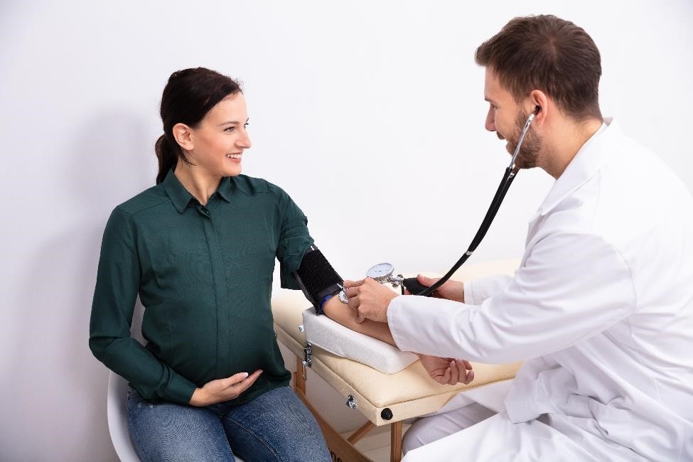 أخصائي رعاية صحية يقوم بفحص ضغط دم المرأة الحامل.
